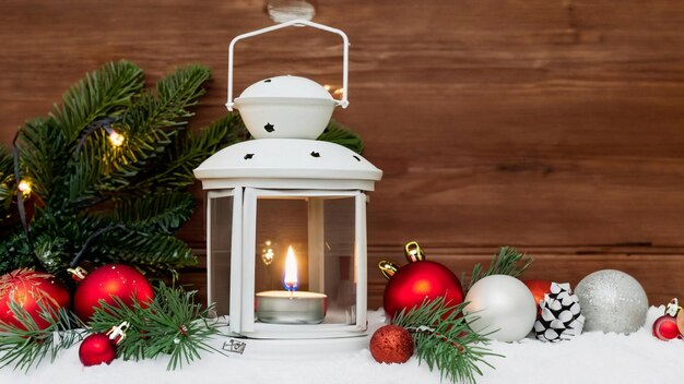 Lanterna di Natale con nevicata appesa a un ramo di abete