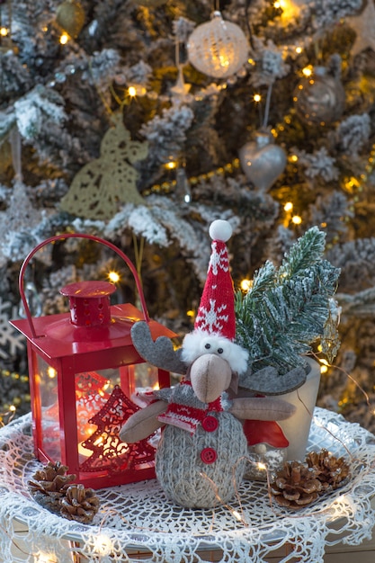 lanterna, rami di abete rosso e alci giocattolo sotto un albero di Natale