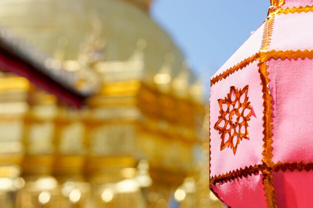 Lanterne tailandesi del primo piano da appendere davanti alla pagoda dorata al tempio tailandese sotto il fondo del cielo blu