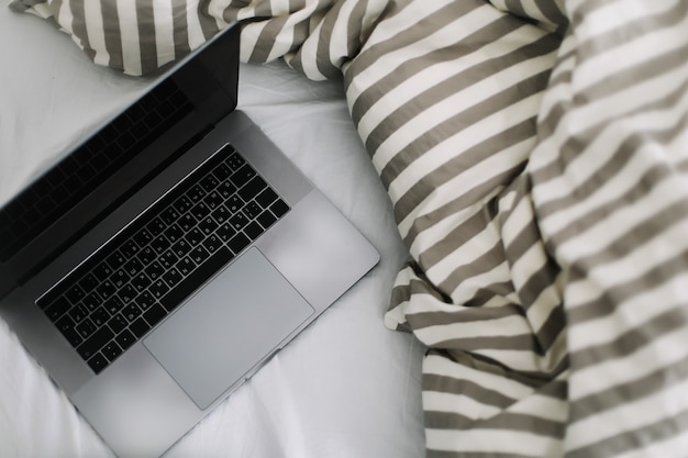 laptop a letto su lenzuola bianche lavora a casa concept home