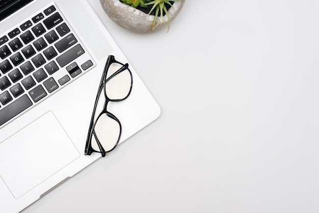 Laptop con occhiali da lettura su sfondo bianco con spazio per copiare o stampare