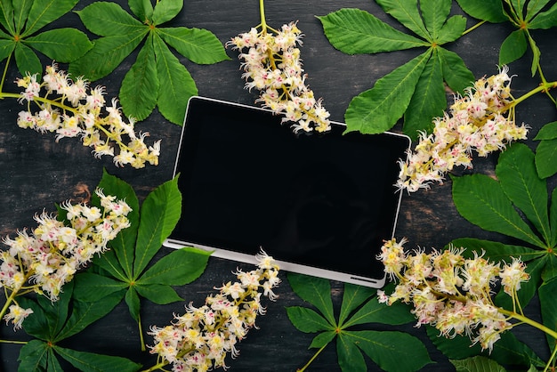 Laptop e fiori di castagno su uno sfondo di legno Vista dall'alto Copia spazio