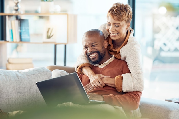 Laptop eccitato e coppia sul divano che legge l'e-mail dalla banca per un investimento in prestito o un mutuo per il successo della casa con l'abbraccio di una donna di colore per il supporto, l'amore e la cura Persone di colore su Internet per il sito Web fintech