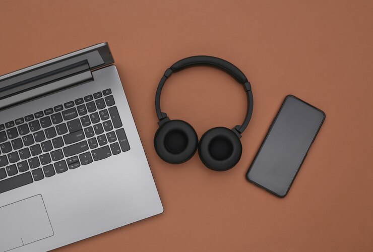 Laptop, smartphone and wireless stereo headphones on a brown background. Top view. Flat lay