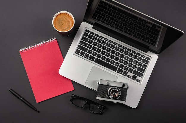 Laptop su un desktop nero con una tazza di caffè, un telefono e un segno wifi funziona nei social network T