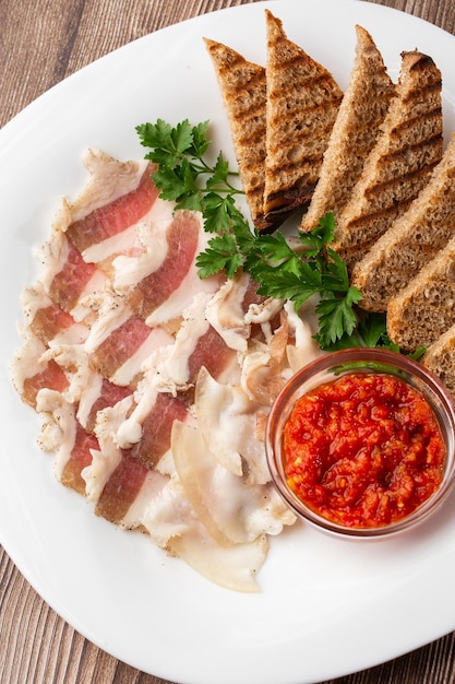 Lardo di maiale tritato crudo con carne una testa d'aglio e pane di segale su uno sfondo di legno per lo spazio della copia Un grosso pezzo di lardo ucraino grasso fresco cibo tradizionale