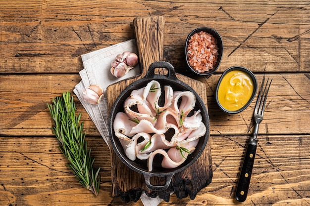 Lardo fresco affettato con sale, aglio e pepe in padella con erbe aromatiche Sfondo in legno Vista dall'alto