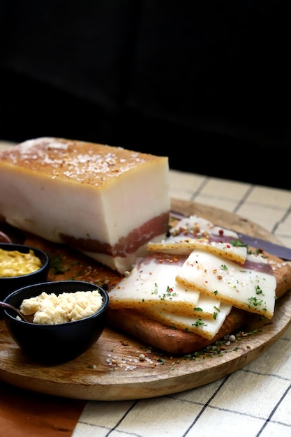 Lardo fresco con strato di carne su una tavola di legno con spezie senape e rafano Delizioso snack Bacon