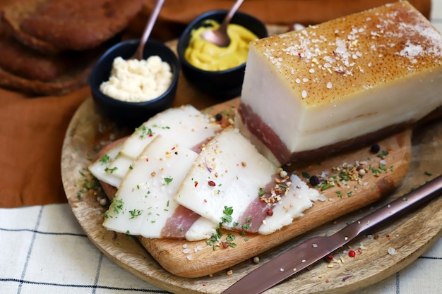 Lardo fresco con strato di carne su una tavola di legno con spezie senape e rafano Delizioso snack Bacon