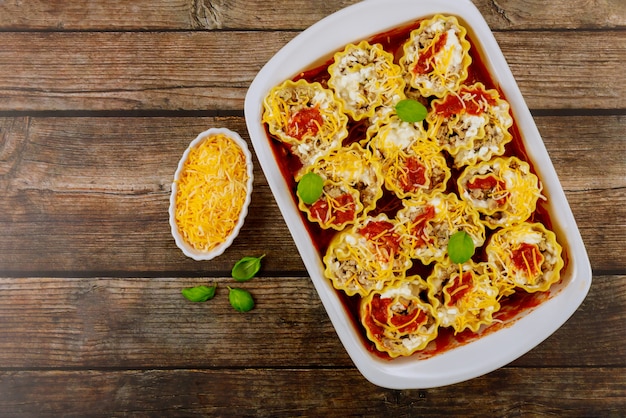 Lasagne al forno italiane tradizionali con formaggio e basilico su fondo di legno