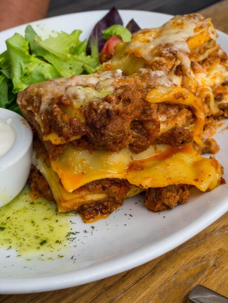 Lasagne al pomodoro e manzo con formaggio a strati tra sfoglie di pasta tradizionale italiana servite su un piatto bianco in un ristorante o bar