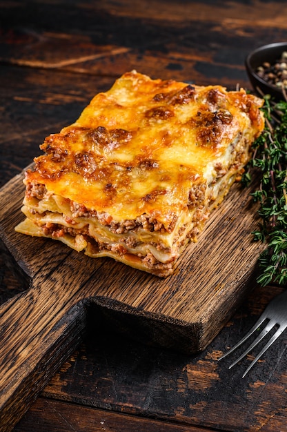 Lasagne all'italiana con ragù alla bolognese e carne di manzo tritata. Fondo di legno scuro. Vista dall'alto.