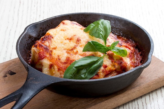 Lasagne in padella di ghisa su tavola di legno Piatto tradizionale italiano