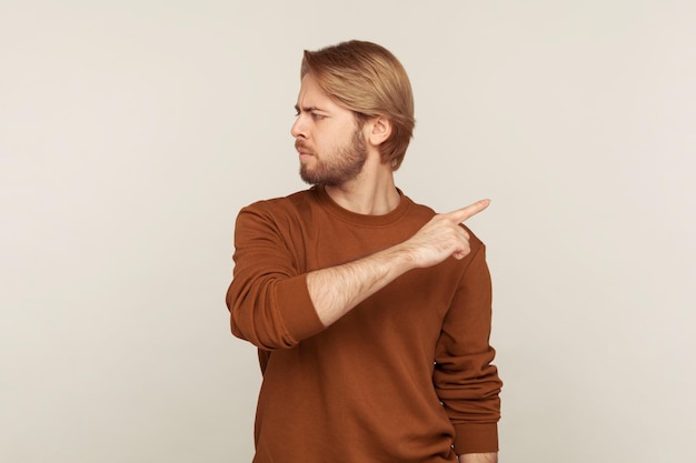 Lasciami Ritratto di uomo irritato sconvolto con la barba in felpa che punta il dito da parte ordinando di uscire