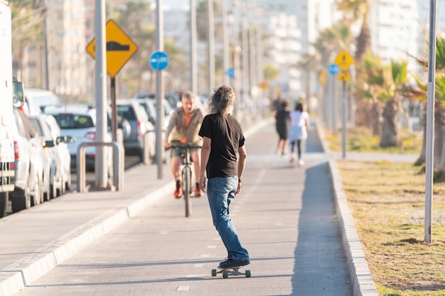 Latino maturo o uomo anziano skateboard sulla pista ciclabile a La Serena al tramonto