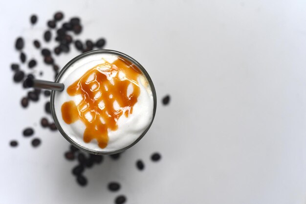 Latte al caramello di ghiaccio con chicchi di caffè isolati su sfondo bianco vista dall'alto primo piano