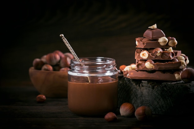 Latte al cioccolato e nocciole fatto in casa spalmato su un barattolo di vetro su fondo di legno scuro