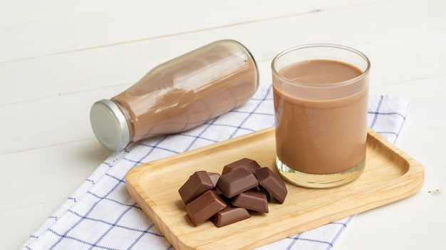 Latte al cioccolato su un tavolo di legno bianco.