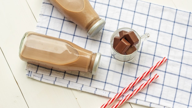 Latte al cioccolato su un tavolo di legno bianco.