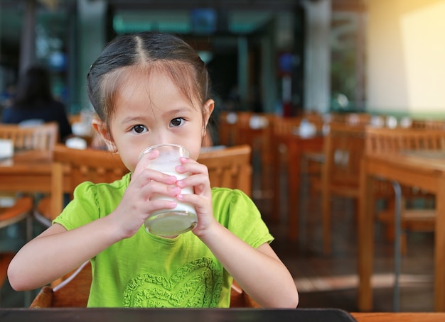 Latte alimentare della piccola ragazza asiatica in ristorante al mattino.