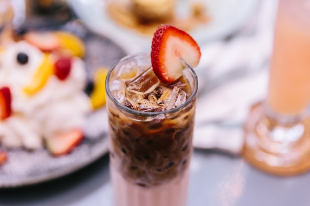 Latte alla fragola ghiacciata che versa con caffè espresso.