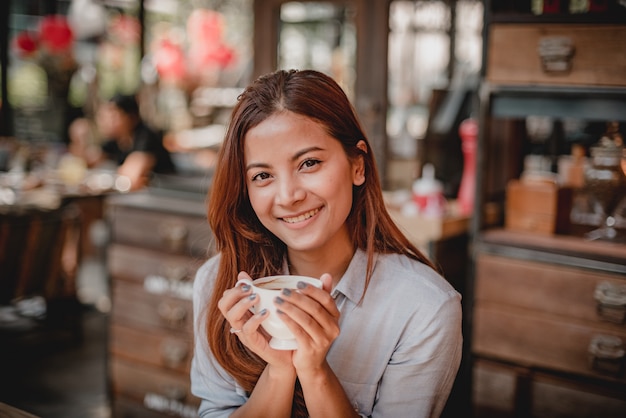 Latte bevente del caffè della donna asiatica nel tono d&#39;annata di colore del caffè