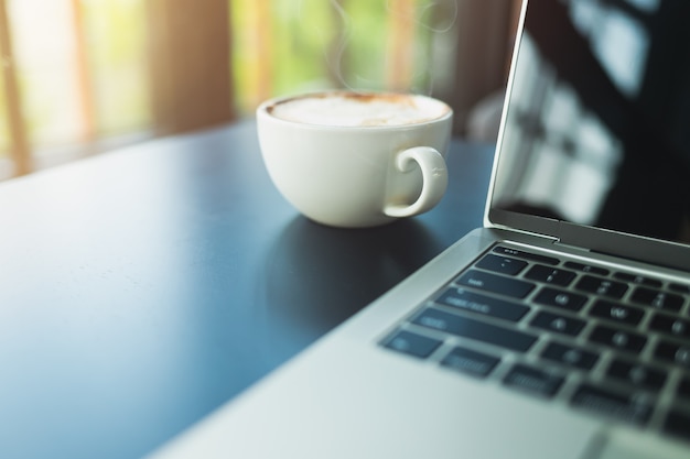 Latte caffè in una tazza di caffè bianco E lato portatile Su un tavolo di legno nero