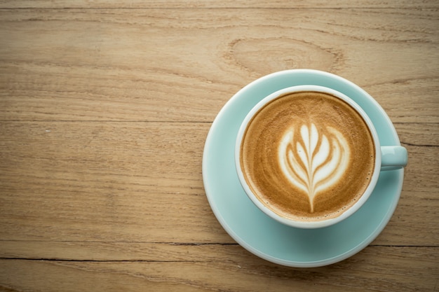 Latte caldo del caffè con la schiuma del latte di arte del latte in tazza della tazza sullo scrittorio di legno sulla vista superiore. Come colazione In una caffetteria al bar, durante il concetto di lavoro d'affari