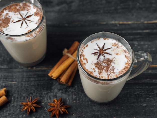 Latte casalingo del tè con cannella e anice su fondo nero rustico di legno in tazza di vetro