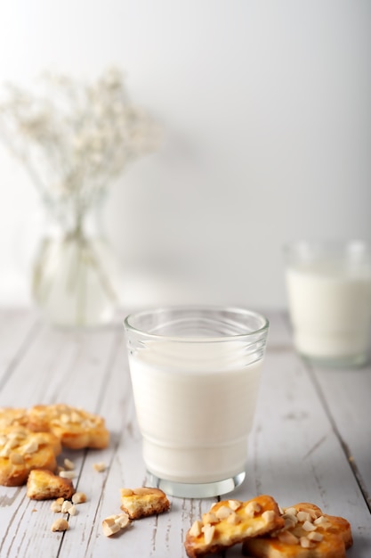 Latte con biscotti fatti in casa appena sfornati con arachidi su sfondo chiaro