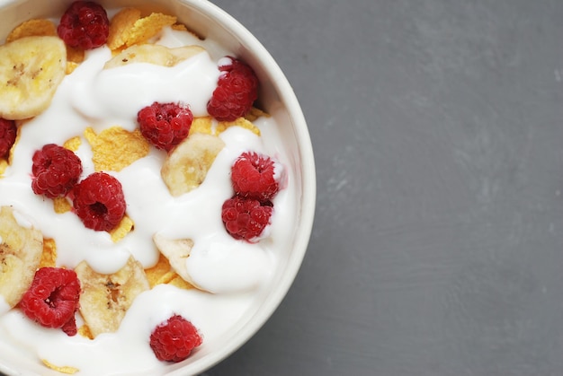 Latte con Cereali e Frutta. Colazione salutare. Ciotola di muesli con latte o yogurt su sfondo grigio con spazio di copia.