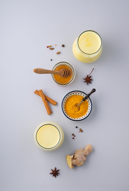 latte con curcuma, spezie e miele su sfondo grigio