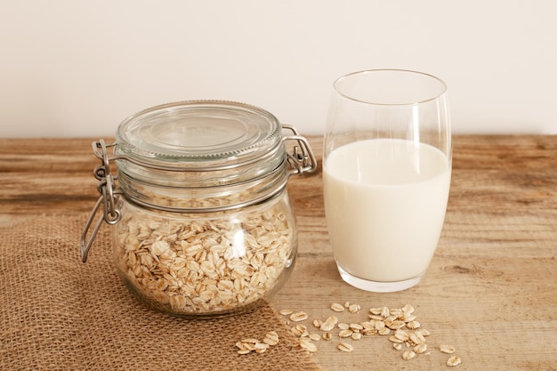 Latte d'avena fresco in vetro, bevanda salutare vegana non casearia. Tavolo in legno, primo piano. Prodotto alternativo, senza lattosio, ingredienti naturali. Sanità, intolleranza al lattosio.