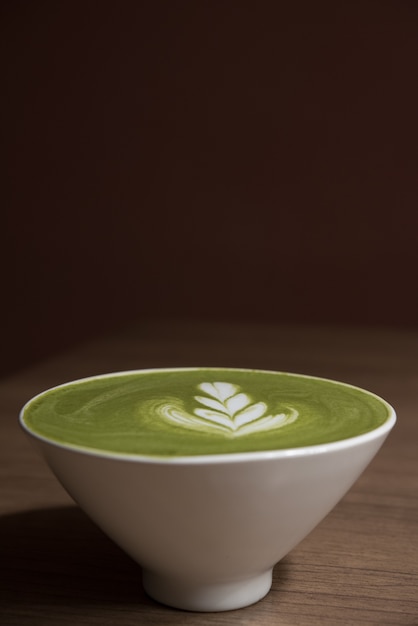 latte del tè verde in tazza di ceramica bianca sulla tavola di legno con fondo marrone