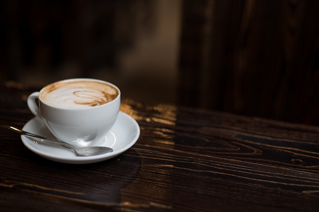 Latte della tazza di caffè su vecchio fondo di legno