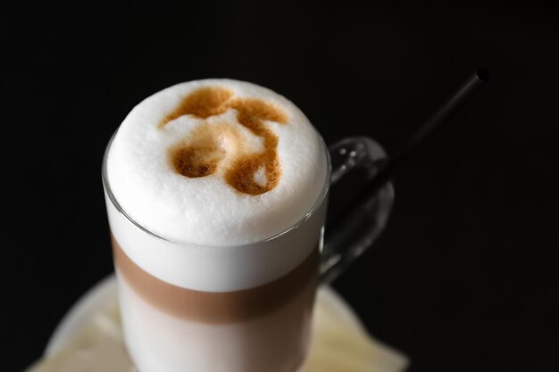 Latte di caffè caldo in bicchiere alto su sfondo nero