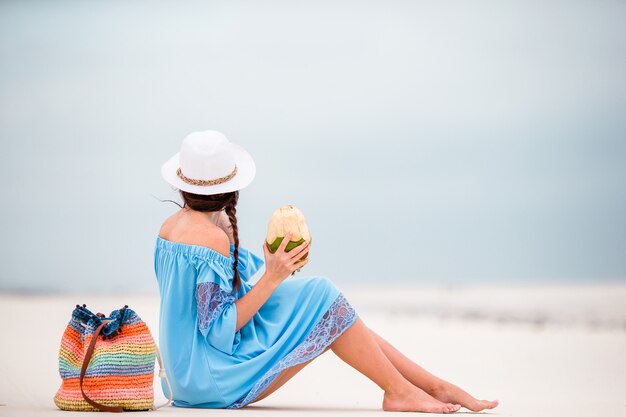 Latte di cocco bevente della giovane donna durante la vacanza tropicale