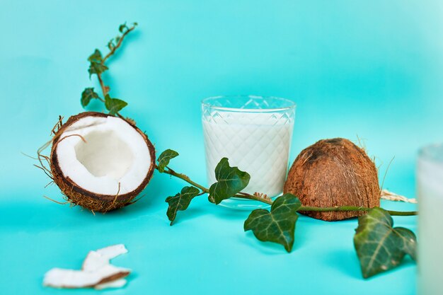 Latte di cocco fresco e sano in un bicchiere sulla parete blu, tipo alternativo di latti vegani, concetto di bevanda biologica sana.