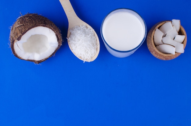 Latte di cocco naturale, trucioli di cocco, scaglie di cocco su sfondo blu. Il concetto di cibo sano.