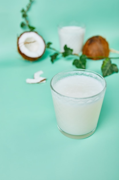 Latte di cocco sano fresco in un bicchiere sulla superficie verde