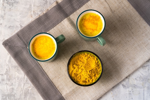 Latte di curcuma dorato con polvere di curcuma in una grande tazza