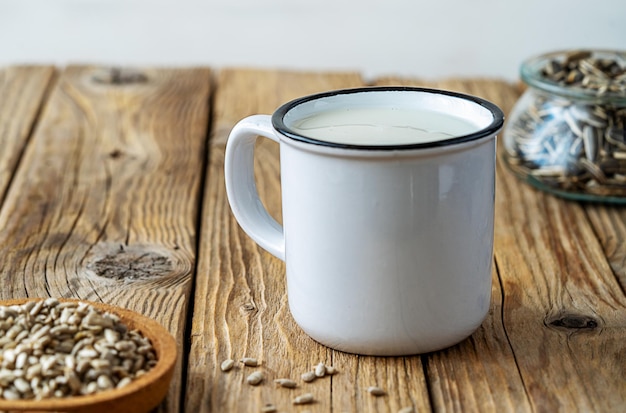 Latte di girasole in tazza con semi crudi su fondo di legno rustico