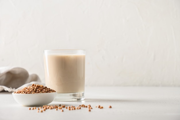 Latte di grano saraceno sano in vetro con ingrediente di grano su sfondo bianco orientamento orizzontale cop...