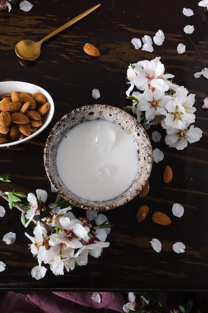 Latte di mandorle con mandorle e fiori di mandorla sul tavolo l'alternativa vegana al latte tradizionale