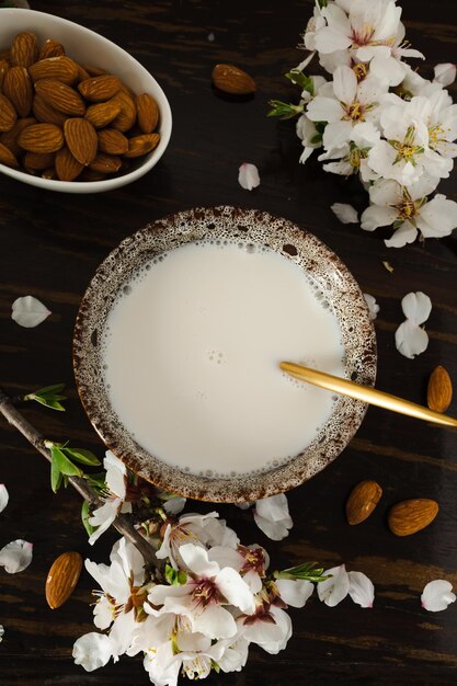 Latte di mandorle con mandorle e fiori di mandorla sul tavolo l'alternativa vegana al latte tradizionale