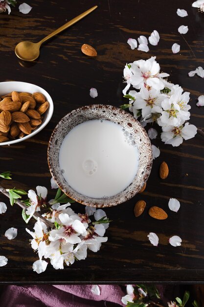 Latte di mandorle con mandorle e fiori di mandorla sul tavolo l'alternativa vegana al latte tradizionale