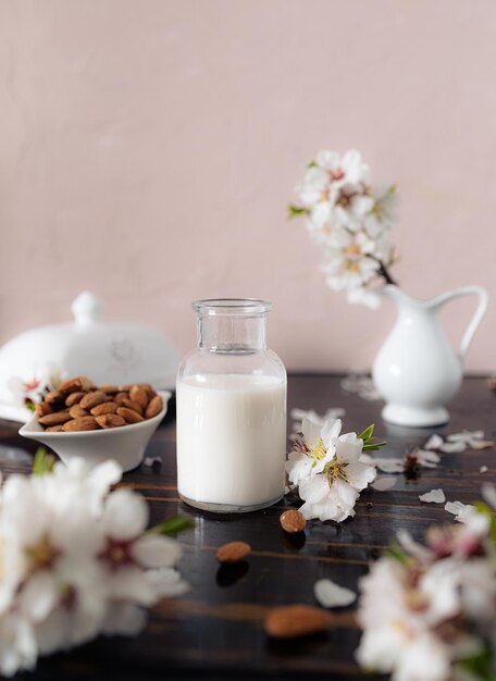 Latte di mandorle con mandorle e fiori di mandorla sul tavolo l'alternativa vegana al latte tradizionale