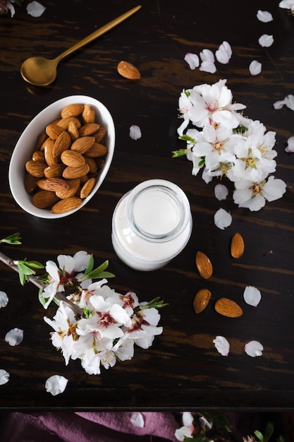 Latte di mandorle con mandorle e fiori di mandorla sul tavolo l'alternativa vegana al latte tradizionale