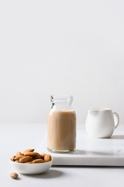 Latte di mandorle fresco in bottiglia di vetro e noci su sfondo grigio