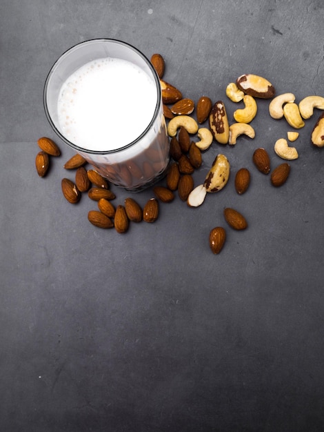 Latte di noci in barattolo di vetro con varie noci su sfondo di cemento